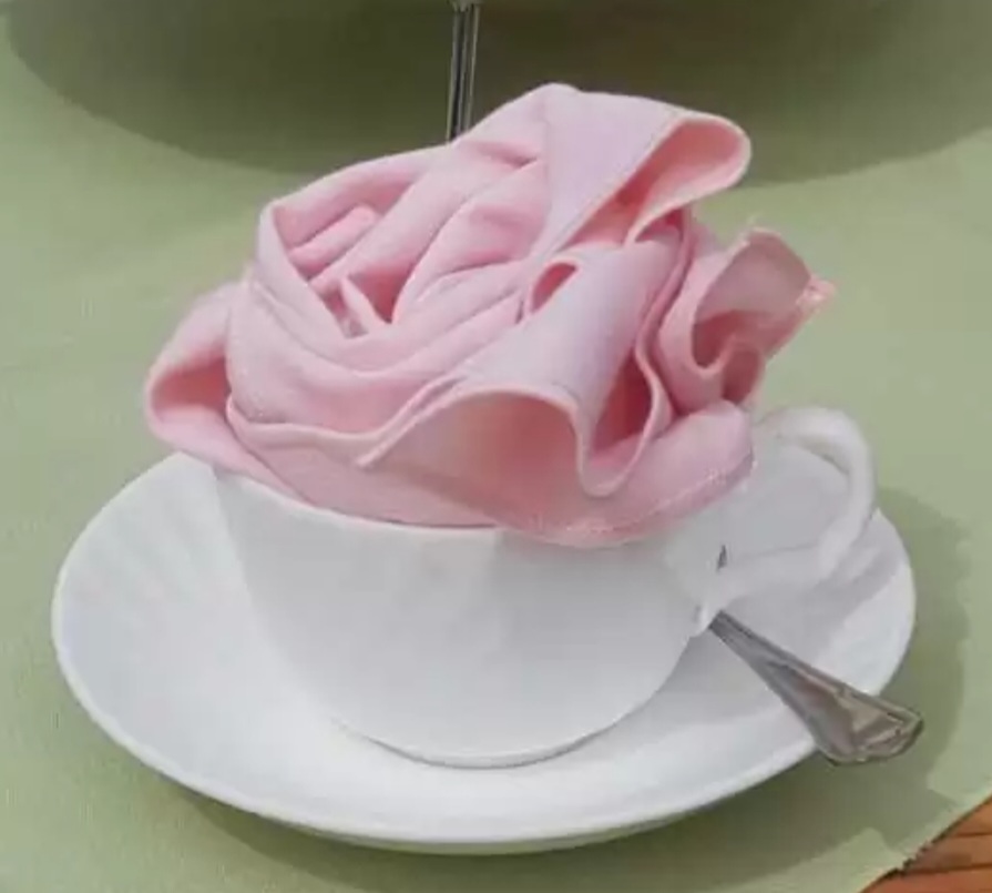 Pink rose napkin in teacup