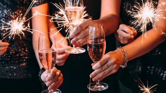 Hands holding champagne flutes and sparklers at a comany Christmas party