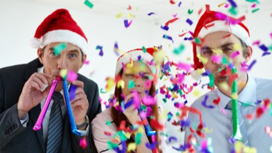 Two office men and a women with streamers ans Santa hats