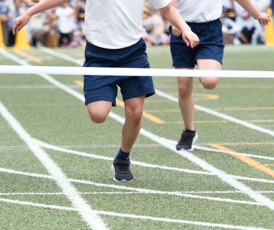 Two boys in PE kit running for the line at a school sports day