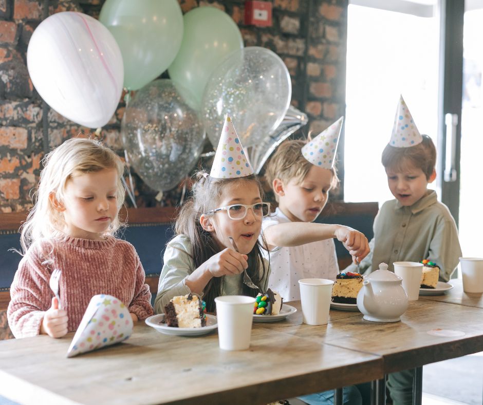 A group of school children in party hats with balloons at a Christmas party