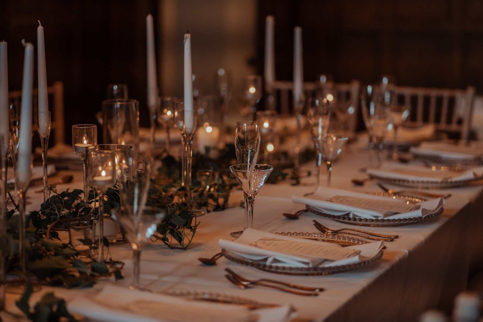 A wedding table laid in white with rose gold cutlery and trailing ivy.