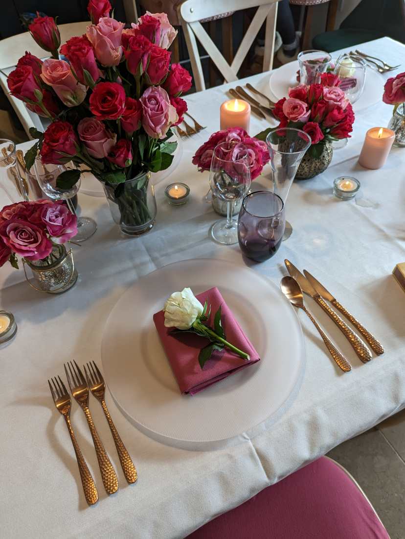 A beautifully laid wedding table with chairs, table linen, flowers and glasses in Viva Magenta wedding colour trend.