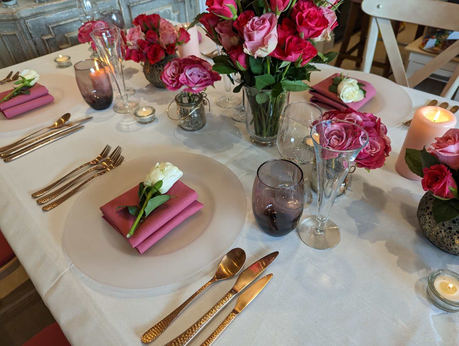 A beautifully laid wedding table with chairs, table linen, flowers and glasses in white with Viva Magenta wedding colour trend accents.