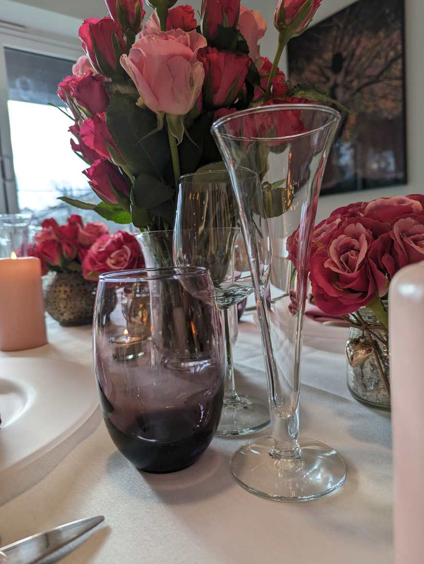 A wedding place setting with a glass tumbler, wine glass and champage flute.