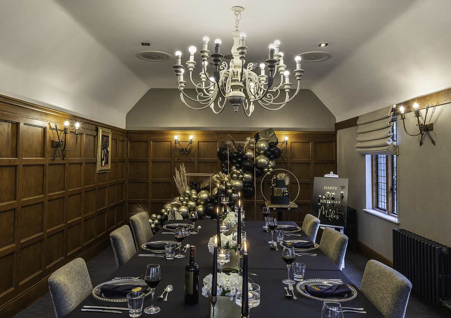 A private dinner party for six people in a wood-pannelled boardroom with a black and gold theme.