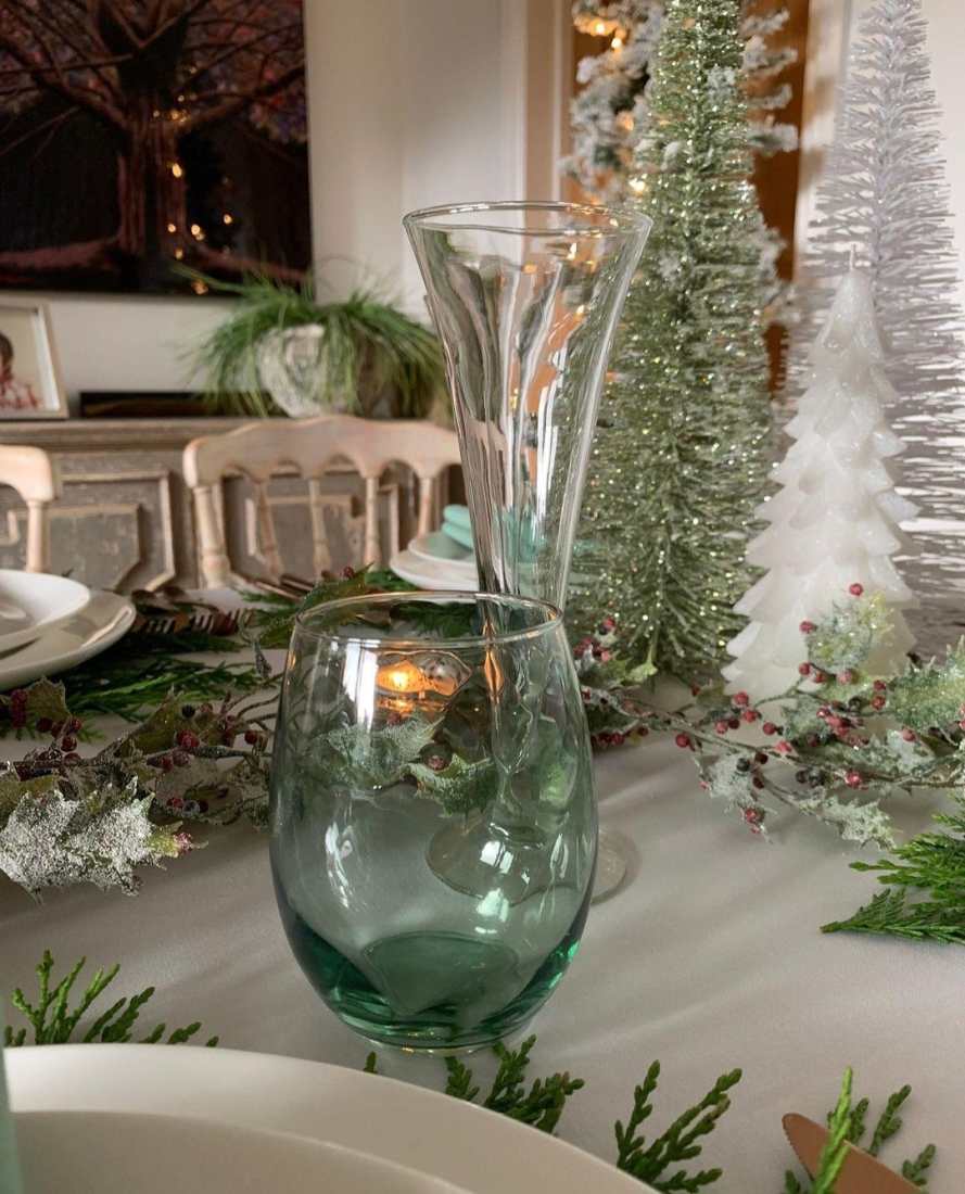 A green glass tumbler at a place setting with a Celedon Christmas theme.