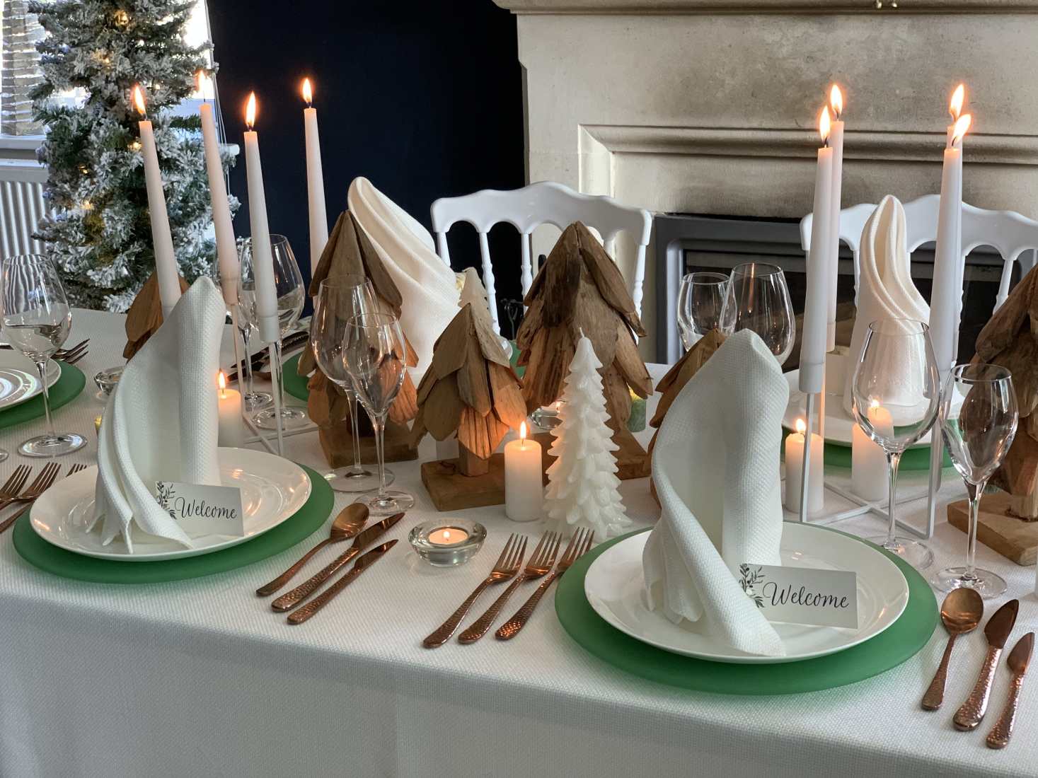 Polar styled Christmas table with white tablecloth and napkins, mint green crockery, lit candles and crystal glasses