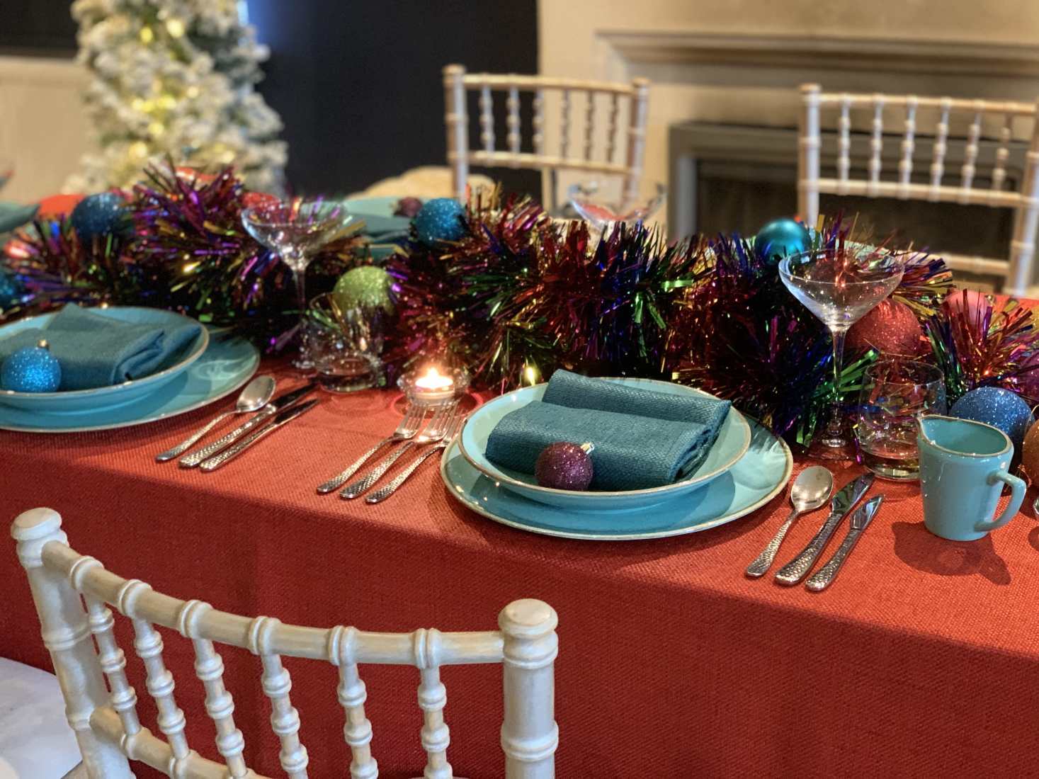 Retro Rainbow styled Christmas table with red tablecloth, aquamarine crockery, plus old school heavy multi-coloured tinseld and glitter baubles.