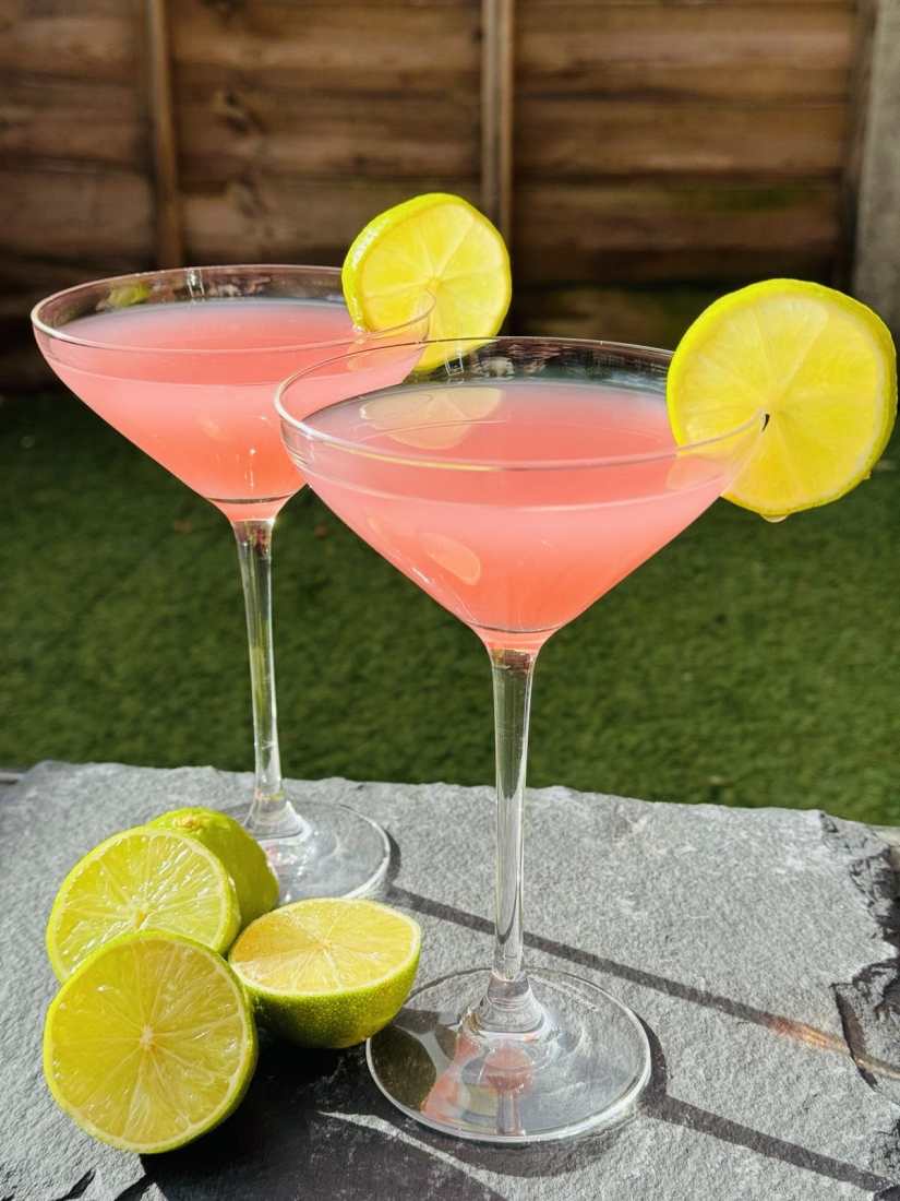 Two Cosmopolitan cocktails served in Martini glasses with lemon wedges.