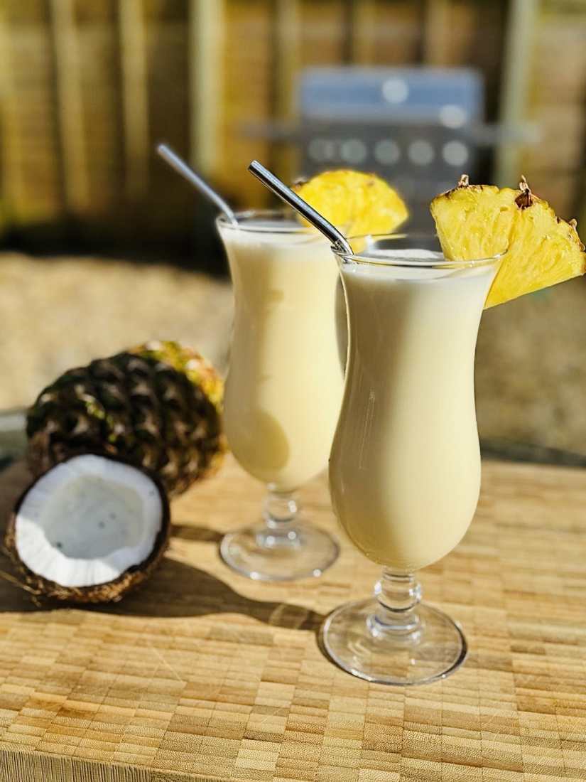 Two Pina Colada cocktails served with pineaple slices and straws.