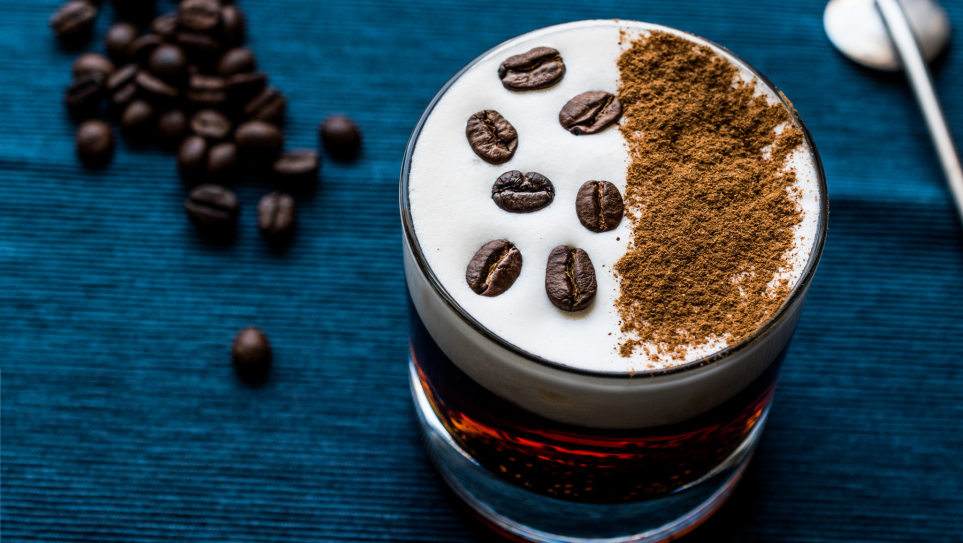 A Whire Russian cocktail served with cocoa powder and coffee beans.