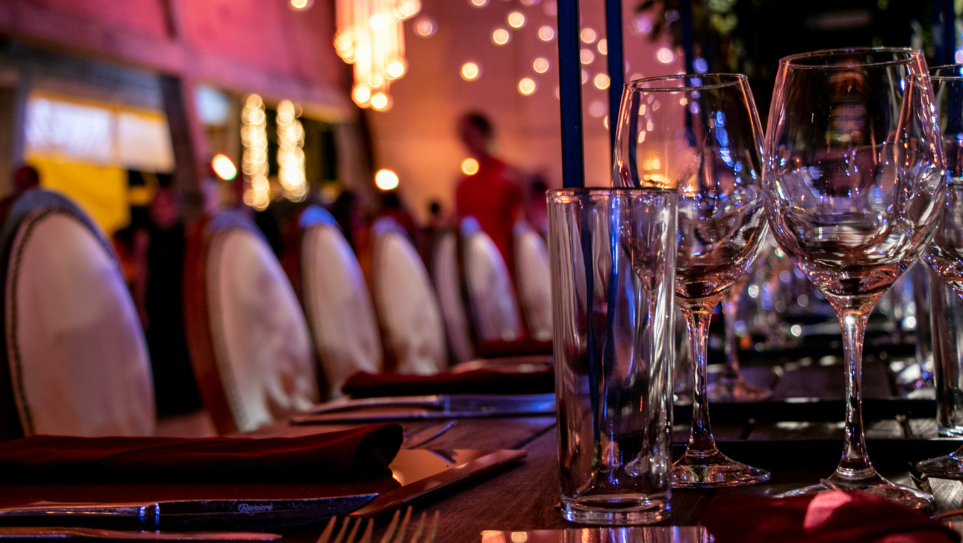 Tables set with crockery, cutlery and glasses with glittering lights in the background.