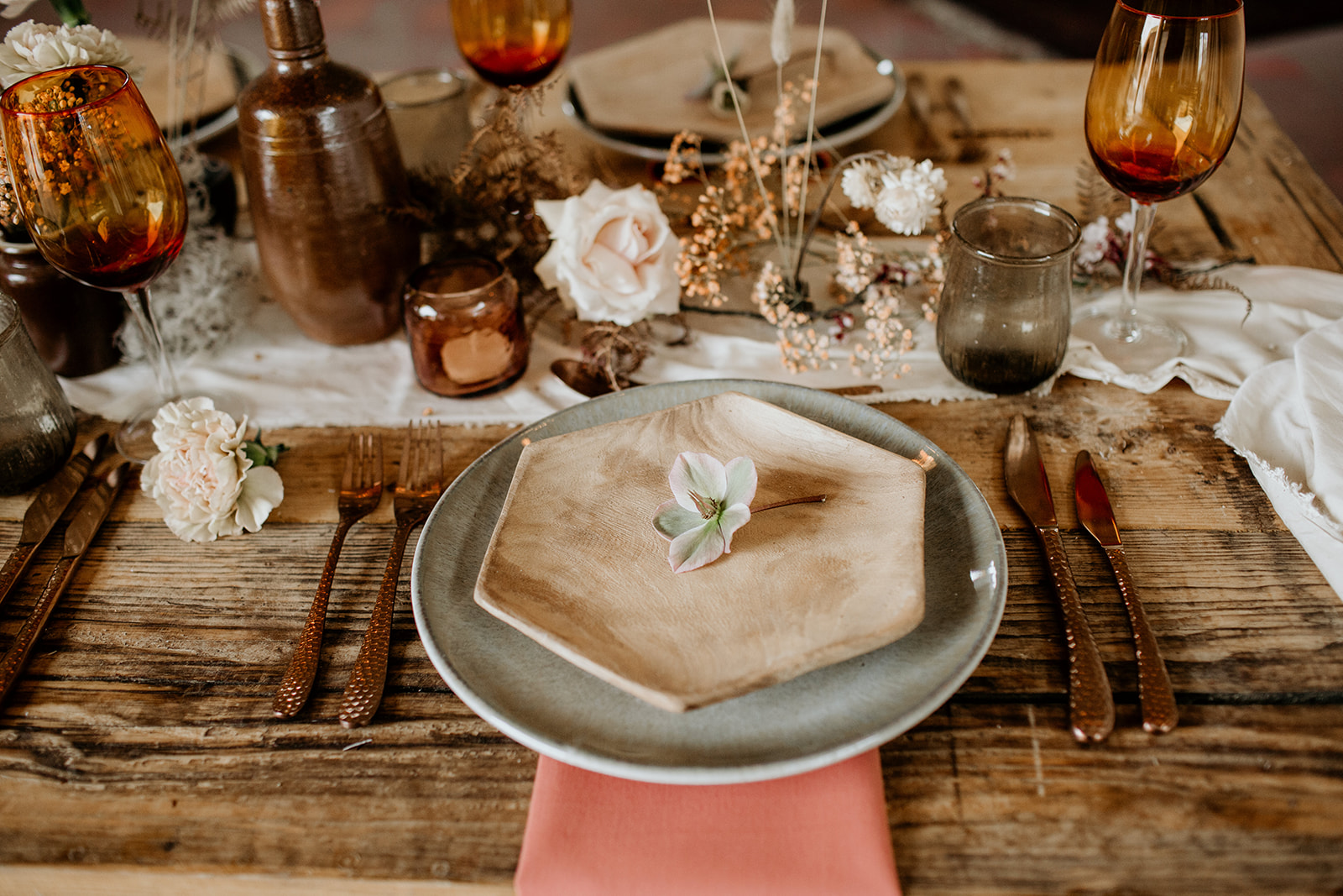 A peaches and cream place setting for a wedding, with plates, glasses, cutlery and flowers.