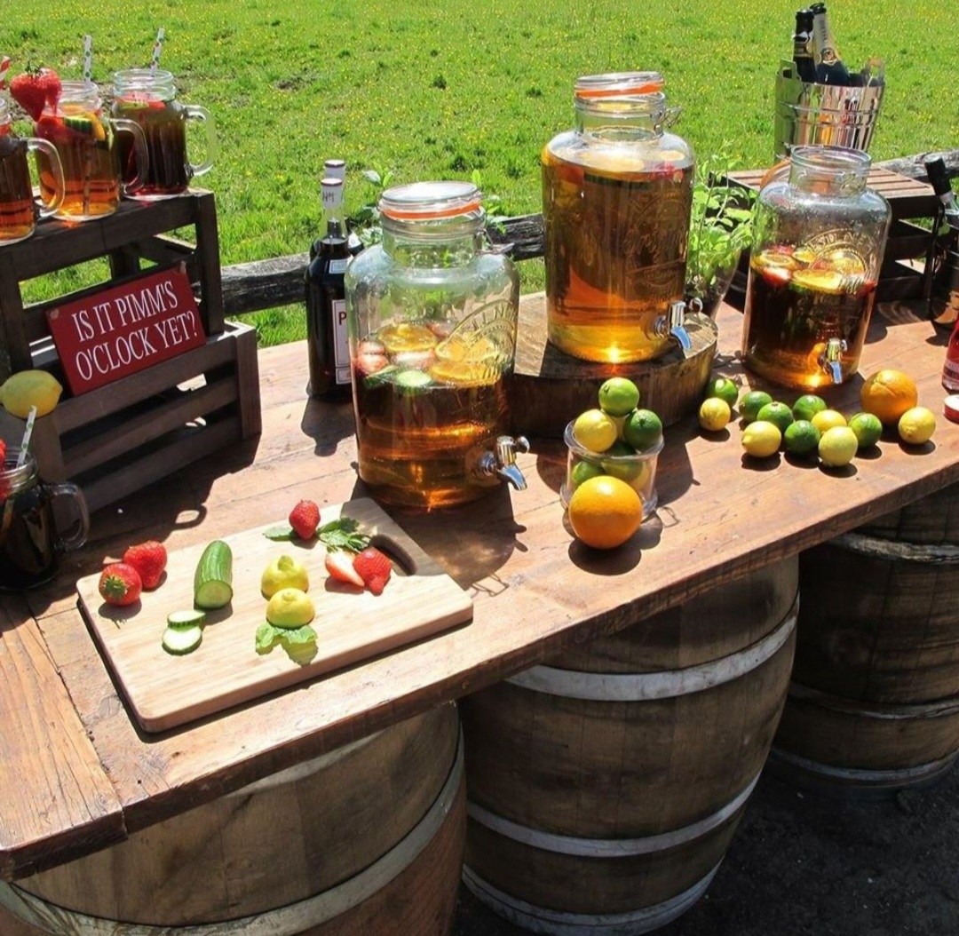 A makeshift rustic table on barrels with food and drinks for al fresco summer dining.