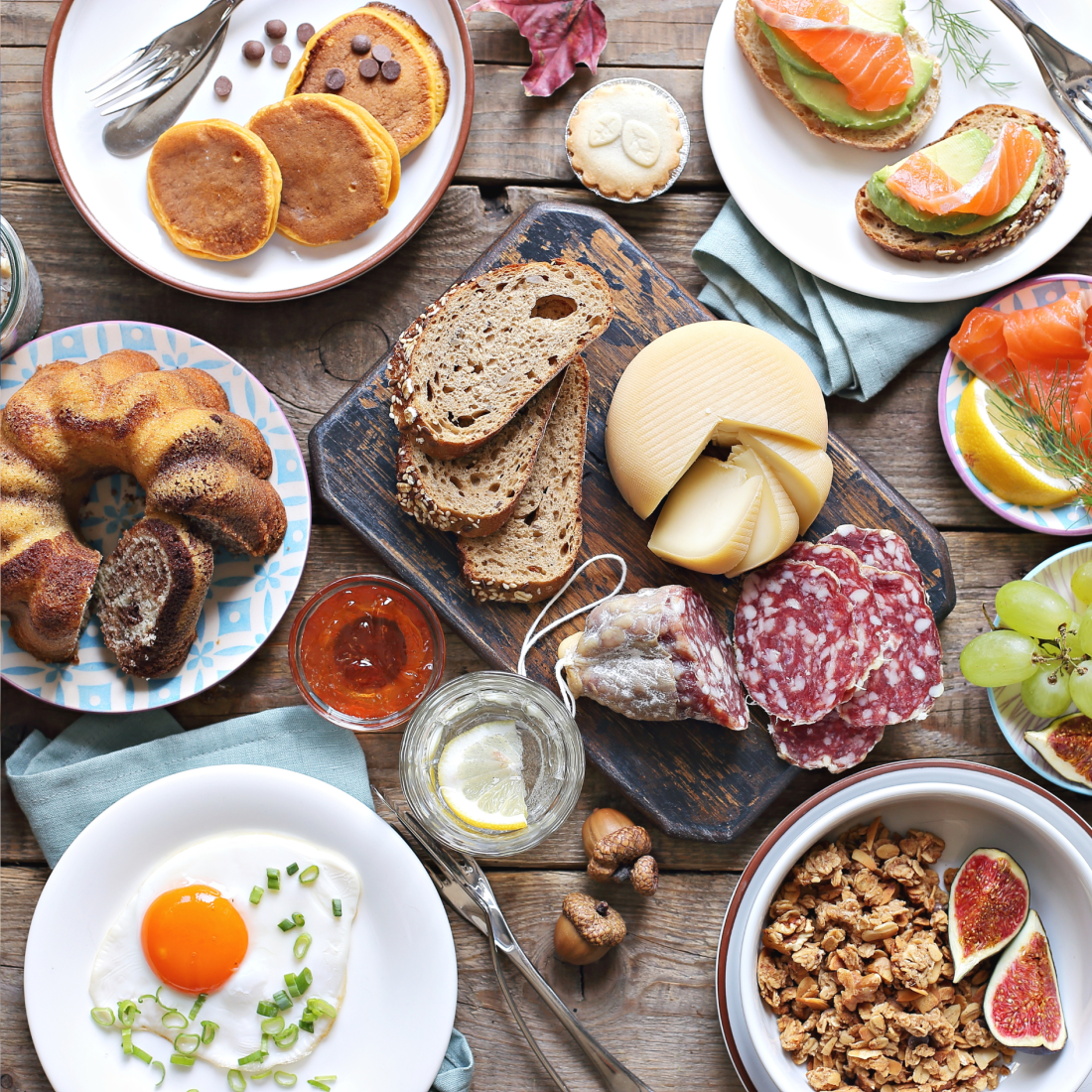 Plates of eggs, granola, smoked salmon bagels, deli meats and bundt cake on a buffet table at a business brunch.