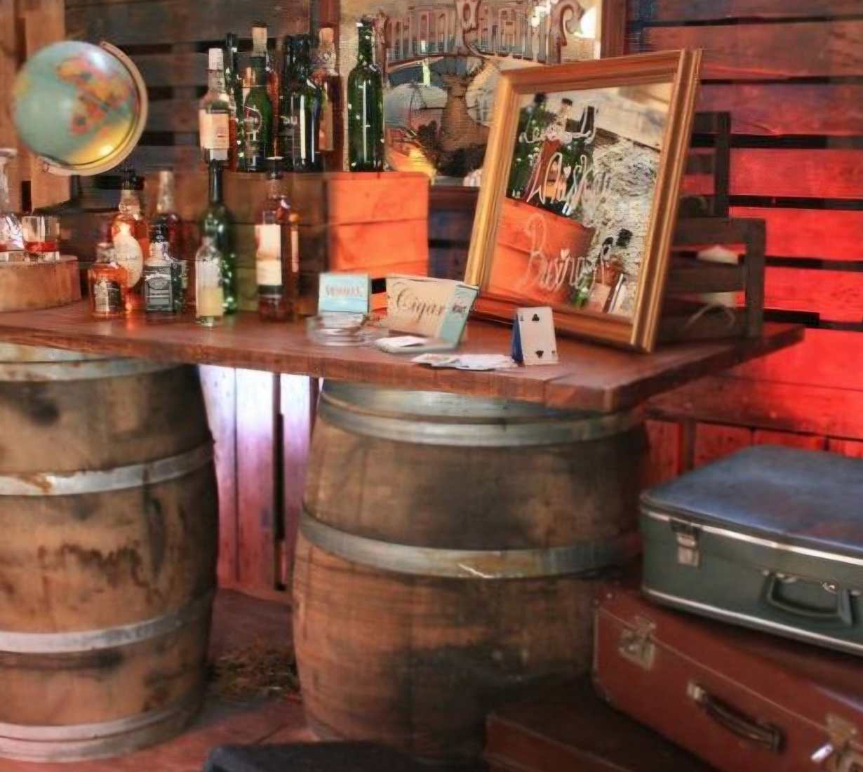 A barrel bar with assorted bottles of spirits and personal items like framed photos and a globe at a celebration of life.
