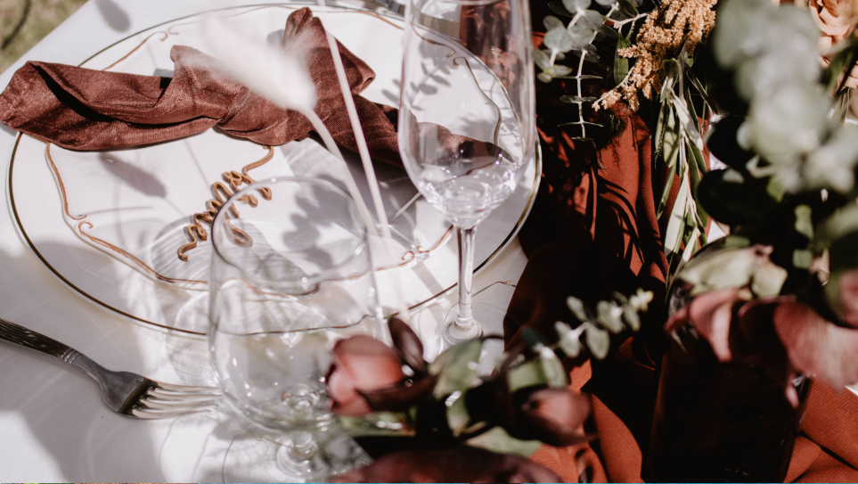 A place setting with a crystal wine glass, white plate and chocolate brown Urbane napkin, demonstrating mocha mousse wedding ideas.