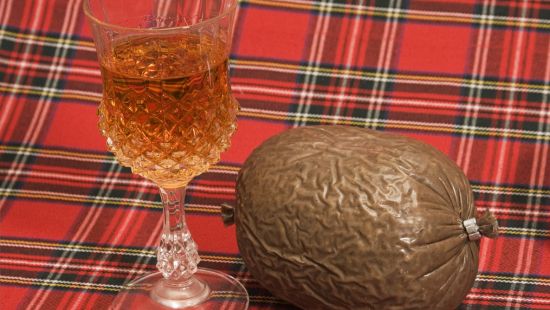 A haggis and glass of whisky on read tartan for a Burns Night party.