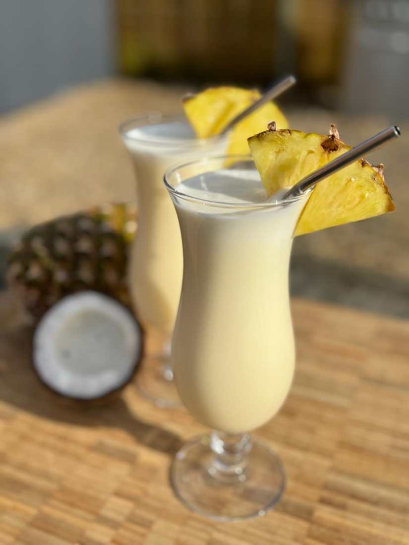 Two Pina Colada cocktails served with slices of pineapple and straws.