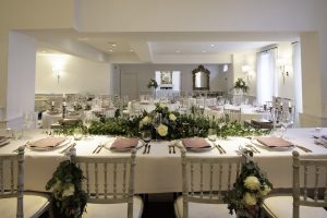 Function room set up for peach weddings, with table settings and floral arrangements.